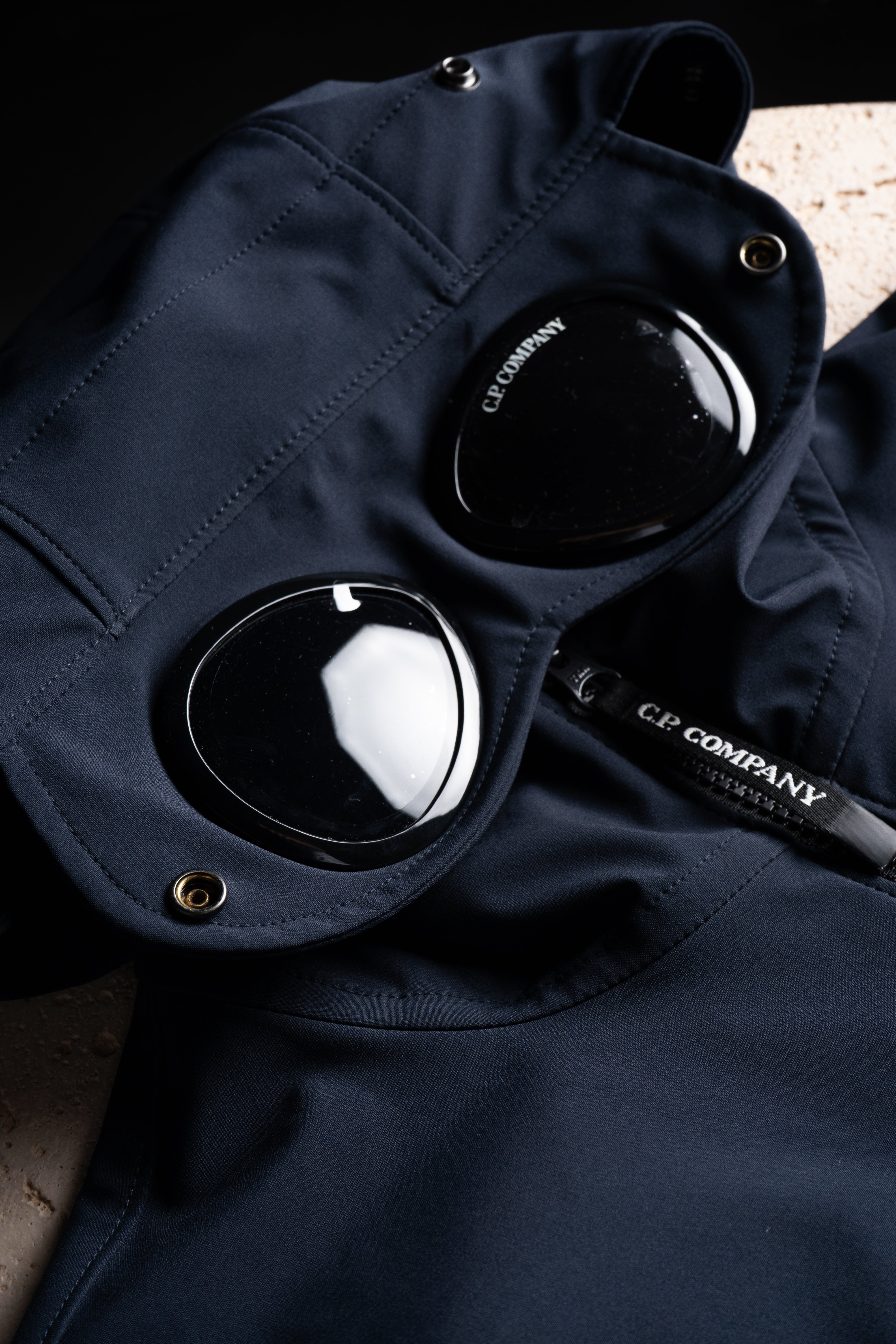 Détails de la Veste CP Company Bleu Marine avec lunettes intégrées à la capuche, offrant style et protection.