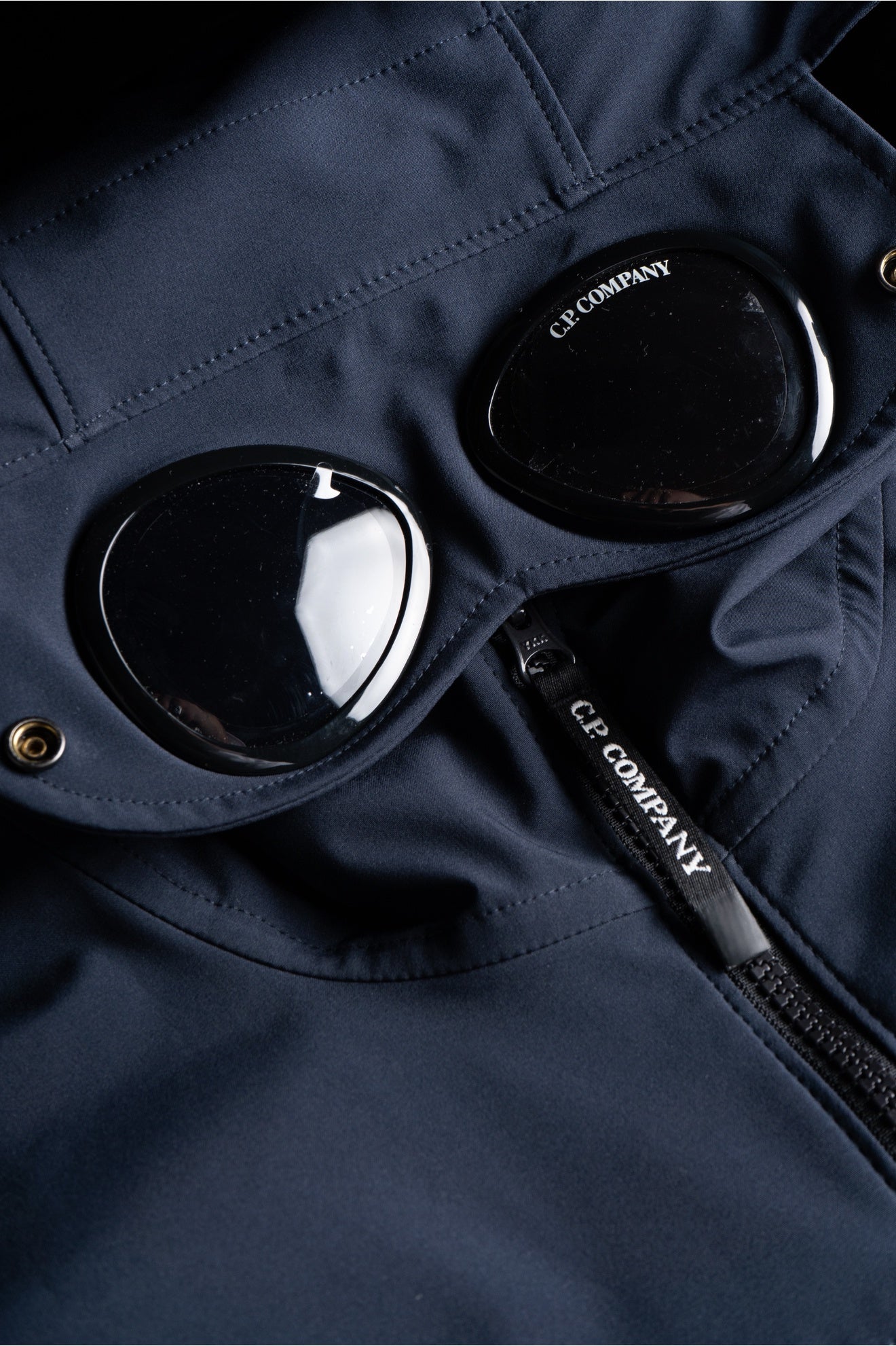 Détail de la capuche de la Veste CP Company Bleu Marine avec lunettes intégrées, alliant style et fonctionnalité.